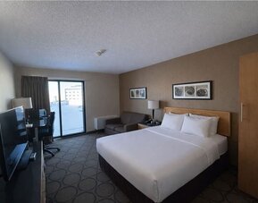 Comfortable king room with premium bedding, sofa, spacious work area, and flat-screen TV at Comfort Inn Baie-Comeau.