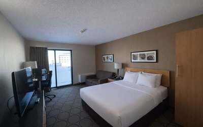 Comfortable king room with premium bedding, sofa, spacious work area, and flat-screen TV at Comfort Inn Baie-Comeau.