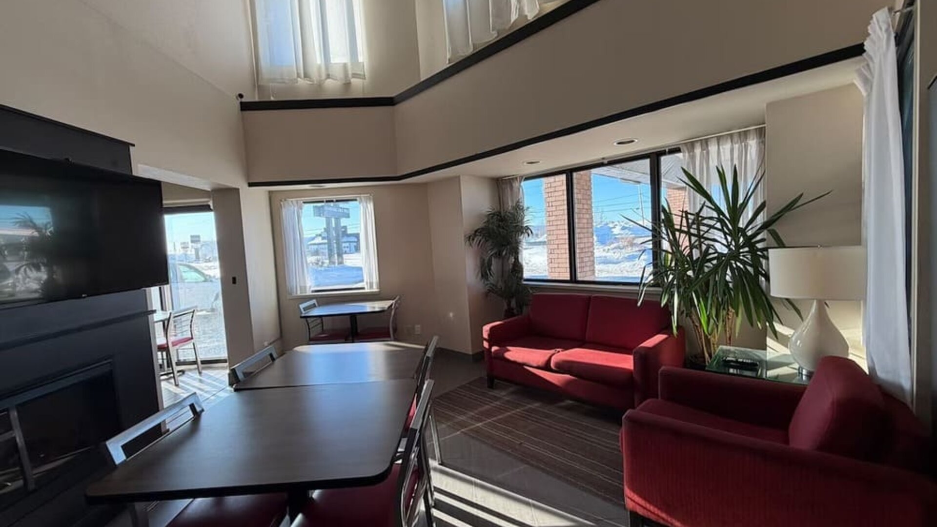 Bright lobby lounge with comfortable seating, dining tables, and a relaxing atmosphere at Comfort Inn Baie-Comeau.