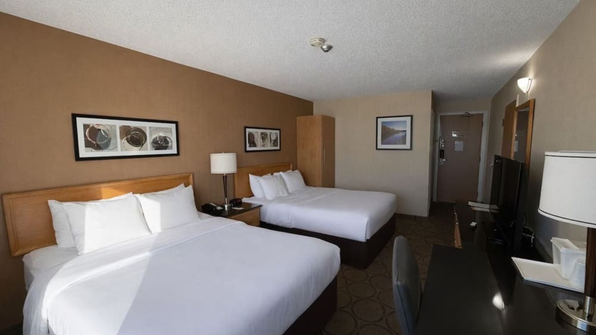 Spacious double queen guest room with premium bedding, work desk, flat-screen TV, and comfortable accommodations at Comfort Inn Baie-Comeau.