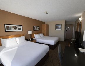 Spacious double queen guest room with premium bedding, work desk, flat-screen TV, and comfortable accommodations at Comfort Inn Baie-Comeau.