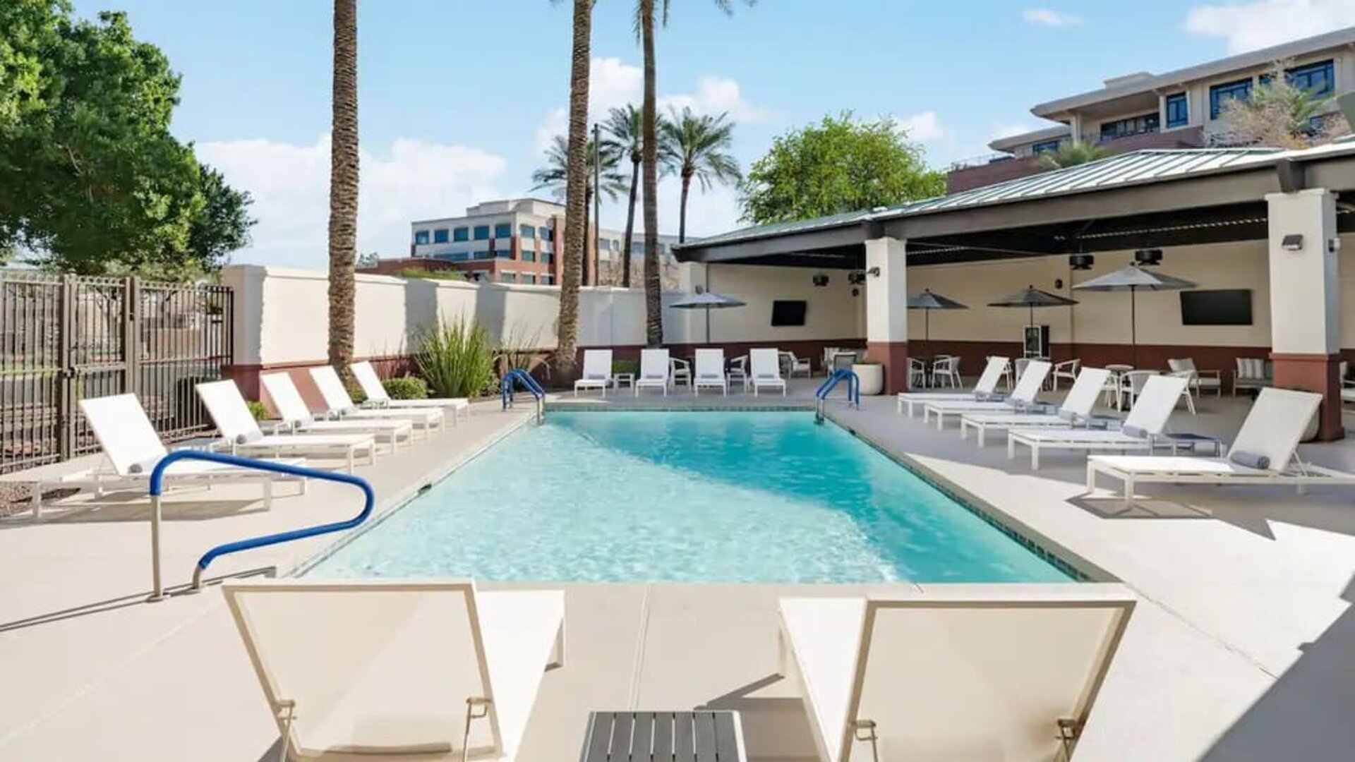 Outdoor swimming pool surrounded by lounge chairs, shaded seating, and sunny relaxation spaces at Hyatt Place Scottsdale/Old Town.