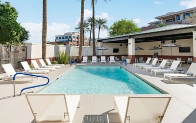 Outdoor swimming pool surrounded by lounge chairs, shaded seating, and sunny relaxation spaces at Hyatt Place Scottsdale/Old Town.