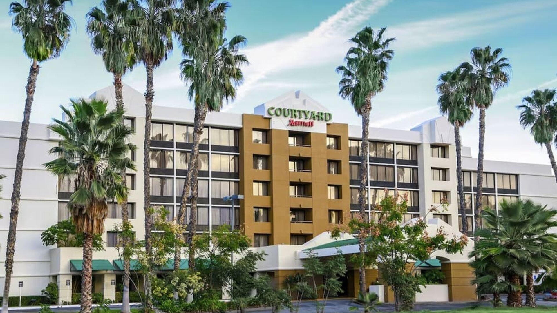 Exterior view of Courtyard Riverside UCR/Moreno Valley Area surrounded by landscaped grounds and palm trees.