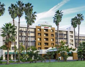 Exterior view of Courtyard Riverside UCR/Moreno Valley Area surrounded by landscaped grounds and palm trees.