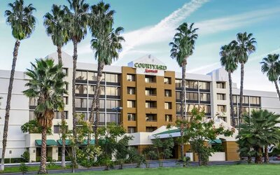 Exterior view of Courtyard Riverside UCR/Moreno Valley Area surrounded by landscaped grounds and palm trees.