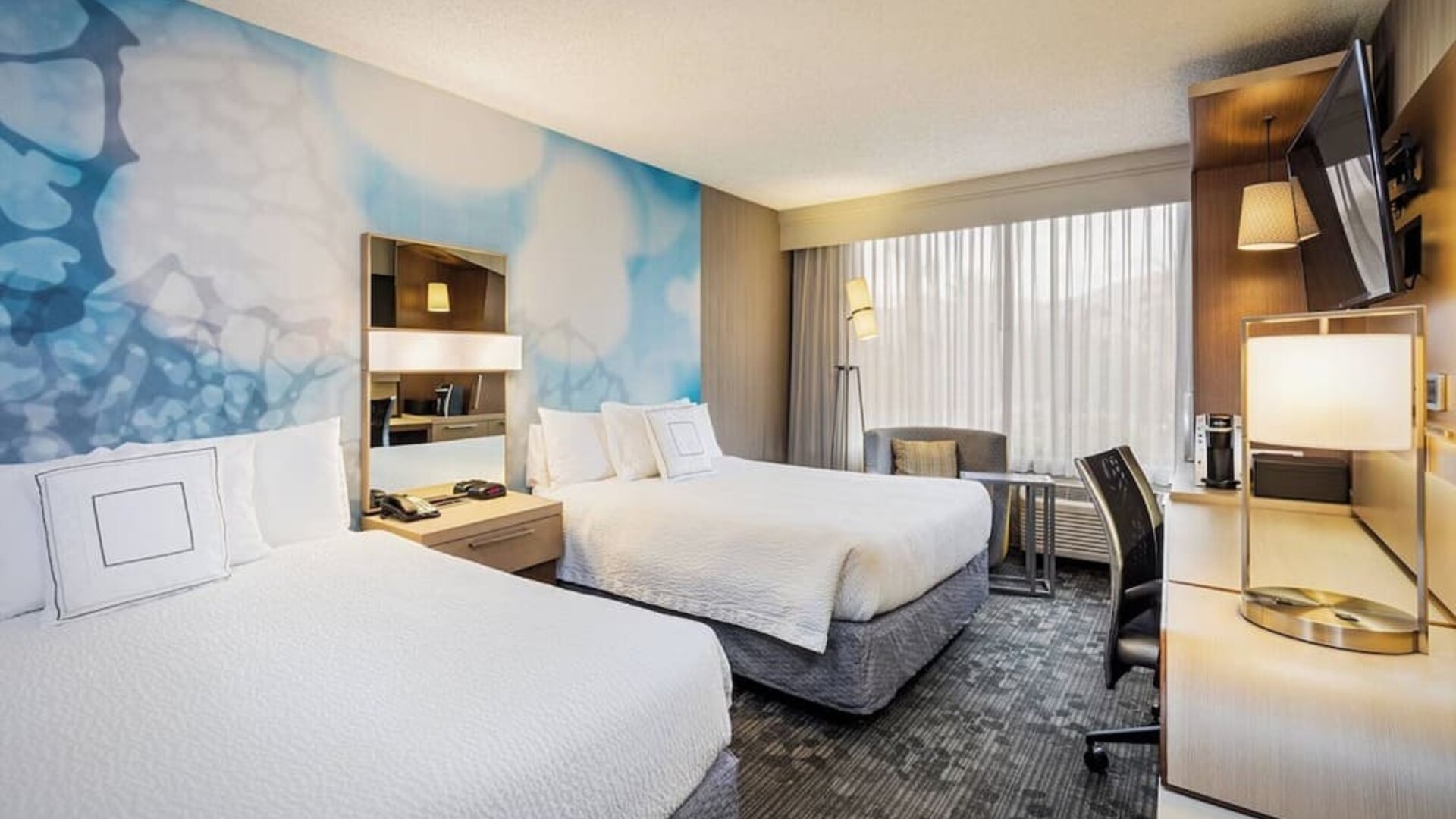 Guest room featuring two queen beds, comfortable seating, a spacious work area, and contemporary décor at Courtyard Riverside UCR/Moreno Valley Area.