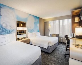 Guest room featuring two queen beds, comfortable seating, a spacious work area, and contemporary décor at Courtyard Riverside UCR/Moreno Valley Area.