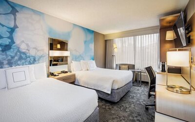 Guest room featuring two queen beds, comfortable seating, a spacious work area, and contemporary décor at Courtyard Riverside UCR/Moreno Valley Area.