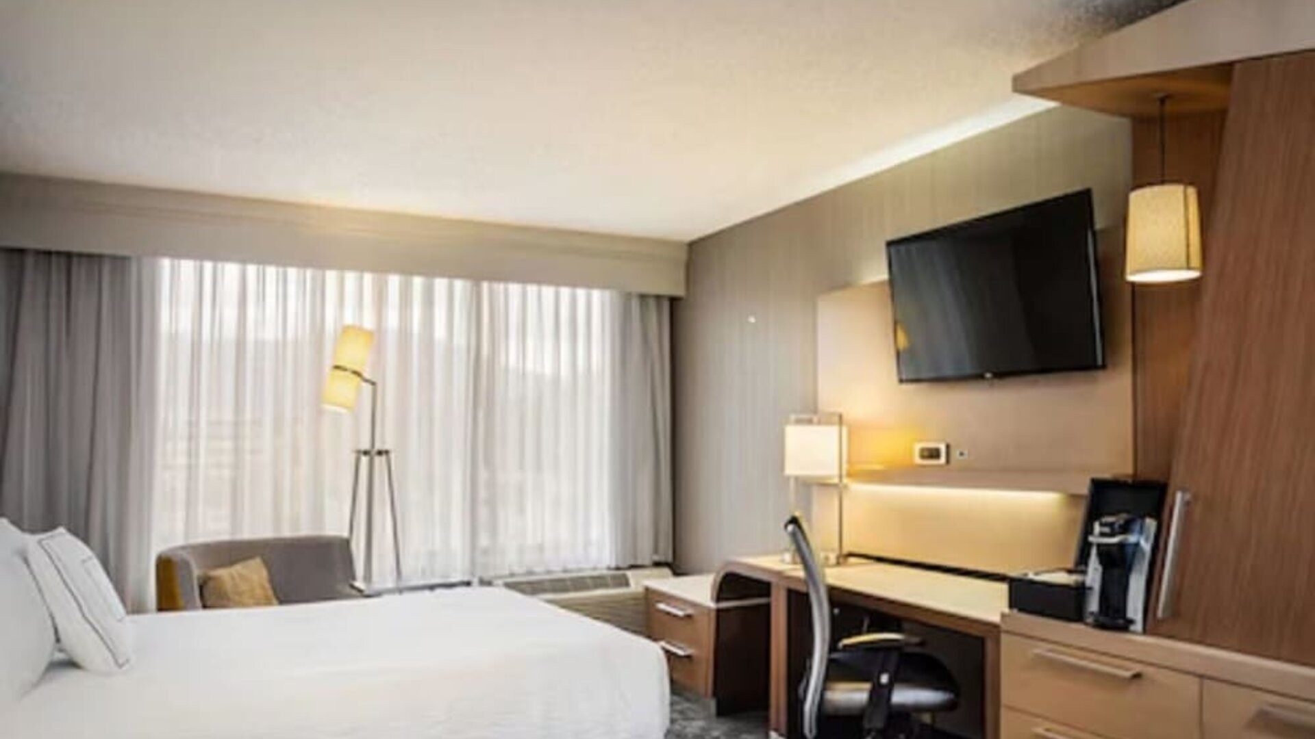 Contemporary king guest room featuring a spacious work desk, HDTV, coffee maker, and comfortable seating at Courtyard Riverside UCR/Moreno Valley Area.