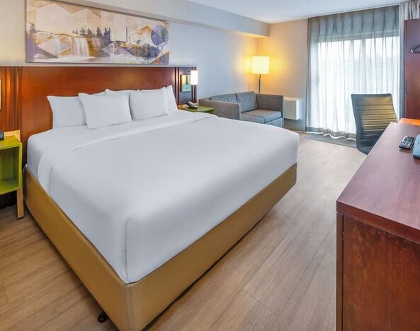 Spacious king guest room with plush bedding, seating area, and work desk at Comfort Inn Sudbury East.