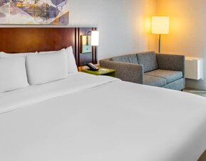 King guest room featuring plush bedding, a cozy loveseat, and modern furnishings at Comfort Inn Sudbury East.