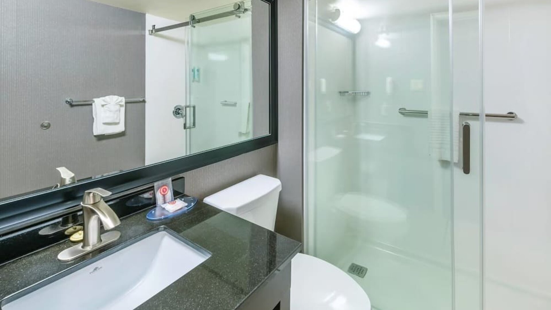 Modern guest bathroom with a walk-in shower, granite vanity, and fresh towels at Comfort Inn Sudbury East.