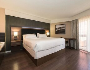 Spacious king guest room with hardwood flooring, modern décor, and natural light at Holiday Inn Express Edmonton Downtown, an IHG Hotel.