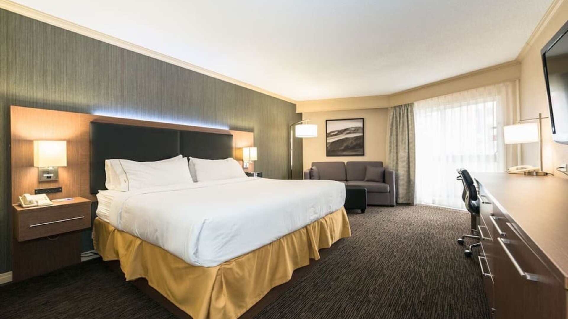 King guest room with natural light, work desk, and comfortable seating at Holiday Inn Express Edmonton Downtown, an IHG Hotel.