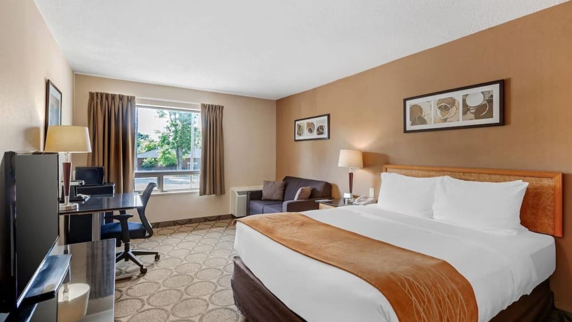 Spacious room with a king bed, sofa, and work desk at Comfort Inn Brantford.
