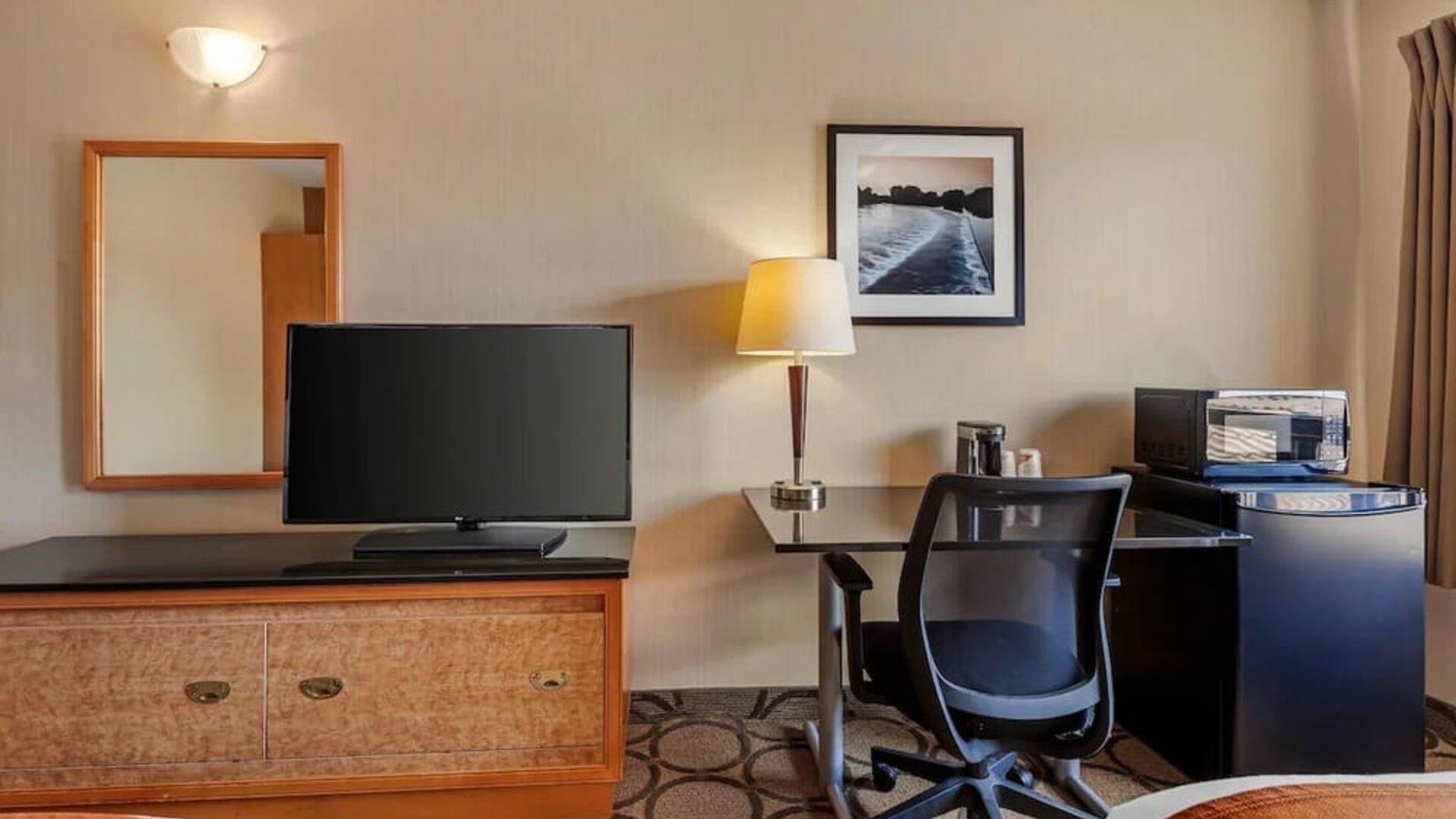 Guest room workspace with a desk, TV, microwave, and mini fridge at Comfort Inn Brantford.