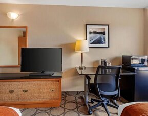 Guest room workspace with a desk, TV, microwave, and mini fridge at Comfort Inn Brantford.