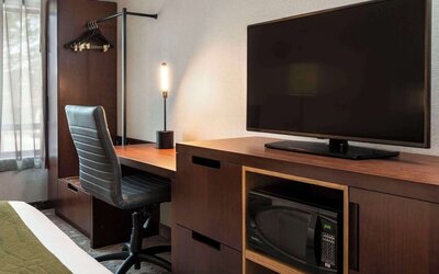 Guest room workspace with a desk, TV, and microwave at Comfort Inn Sault Ste. Marie.