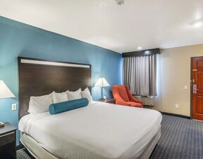 Spacious guest room with a king bed and armchair at Glenridge Inn Glendale Pasadena.