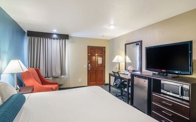 Guest room with a king bed, TV, work desk, and seating area at Glenridge Inn Glendale Pasadena.