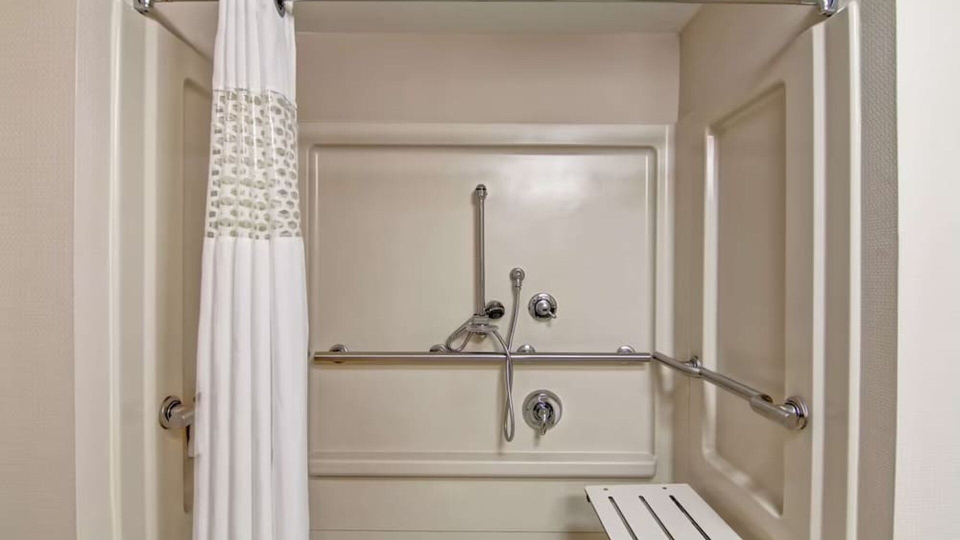 Accessible roll-in shower with grab bars and a shower seat at Hampton Inn & Suites By Hilton Guelph.