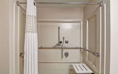 Accessible roll-in shower with grab bars and a shower seat at Hampton Inn & Suites By Hilton Guelph.