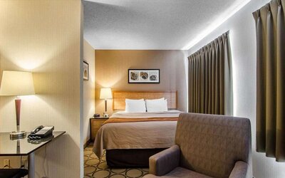 Guest room with a king bed, sofa, and workspace at Comfort Inn Regina.