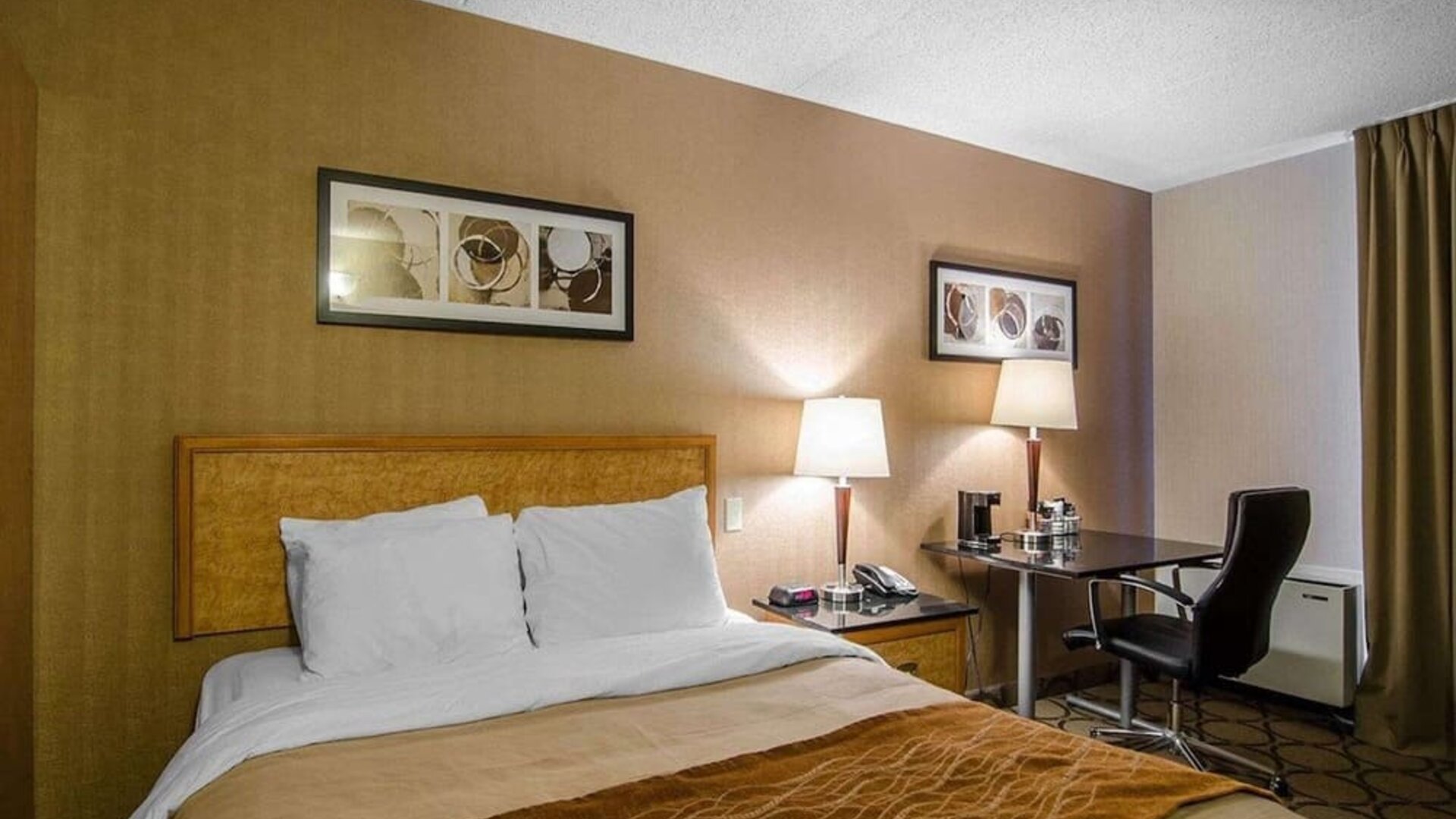 Guest room with a queen bed and work desk at Comfort Inn Swift Current.