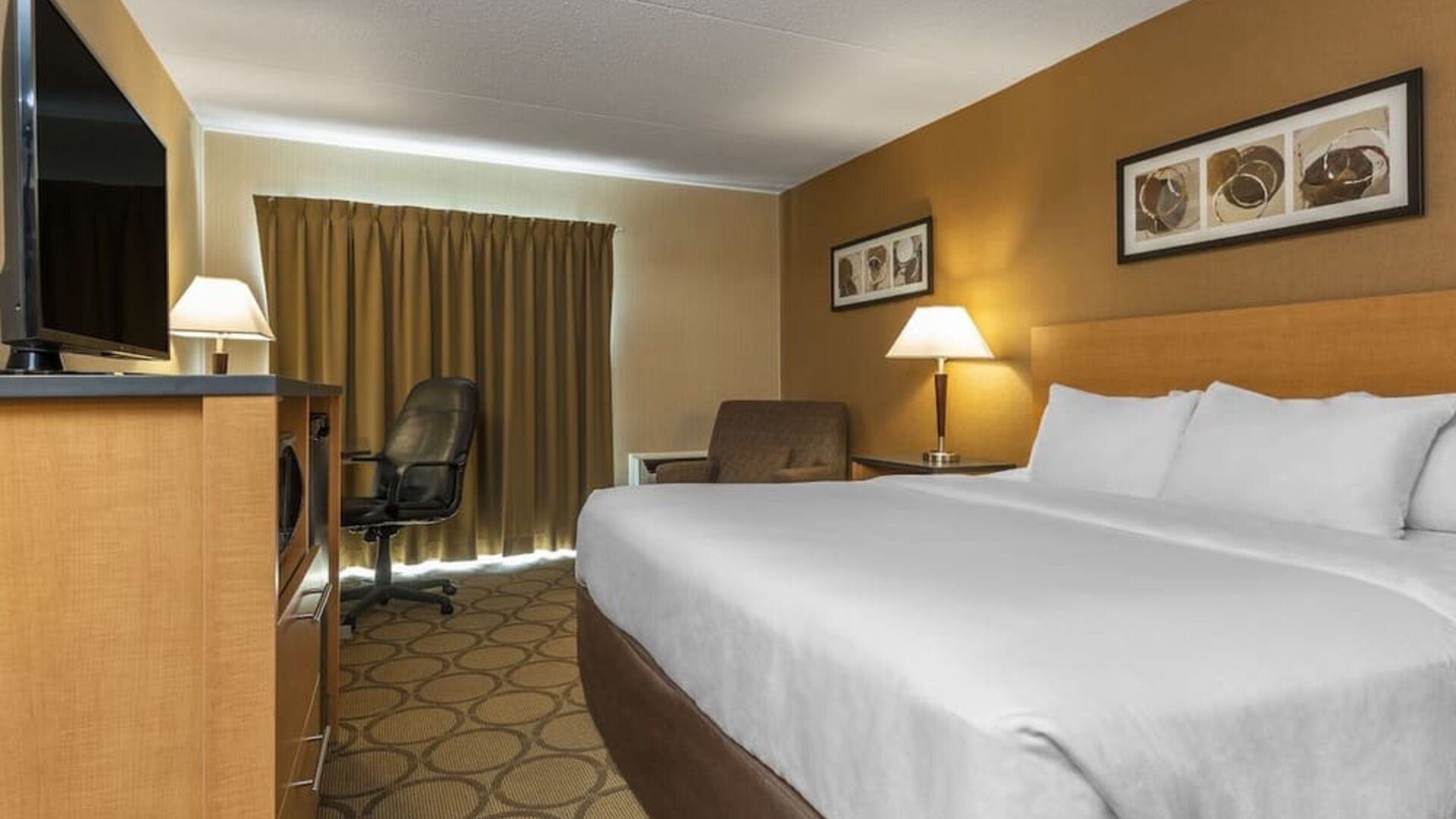 Guest room with a king bed, work desk, and seating area at Comfort Inn Swift Current.