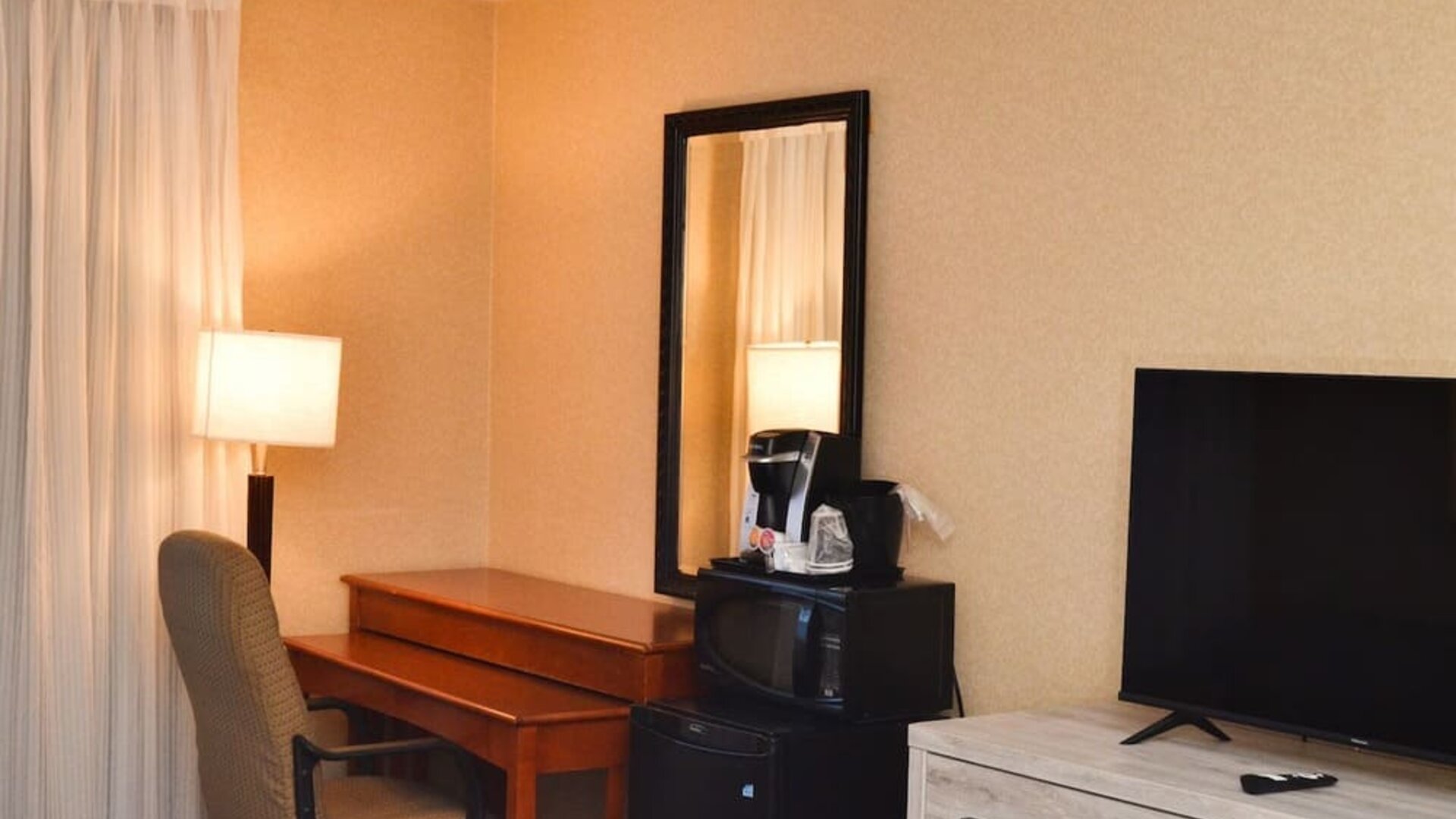 In-room workspace with a desk, coffee maker, and mini fridge at Amenida Residences.