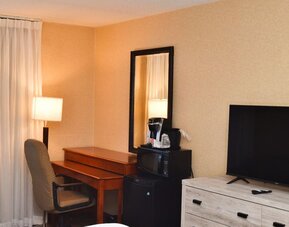 In-room workspace with a desk, coffee maker, and mini fridge at Amenida Residences.