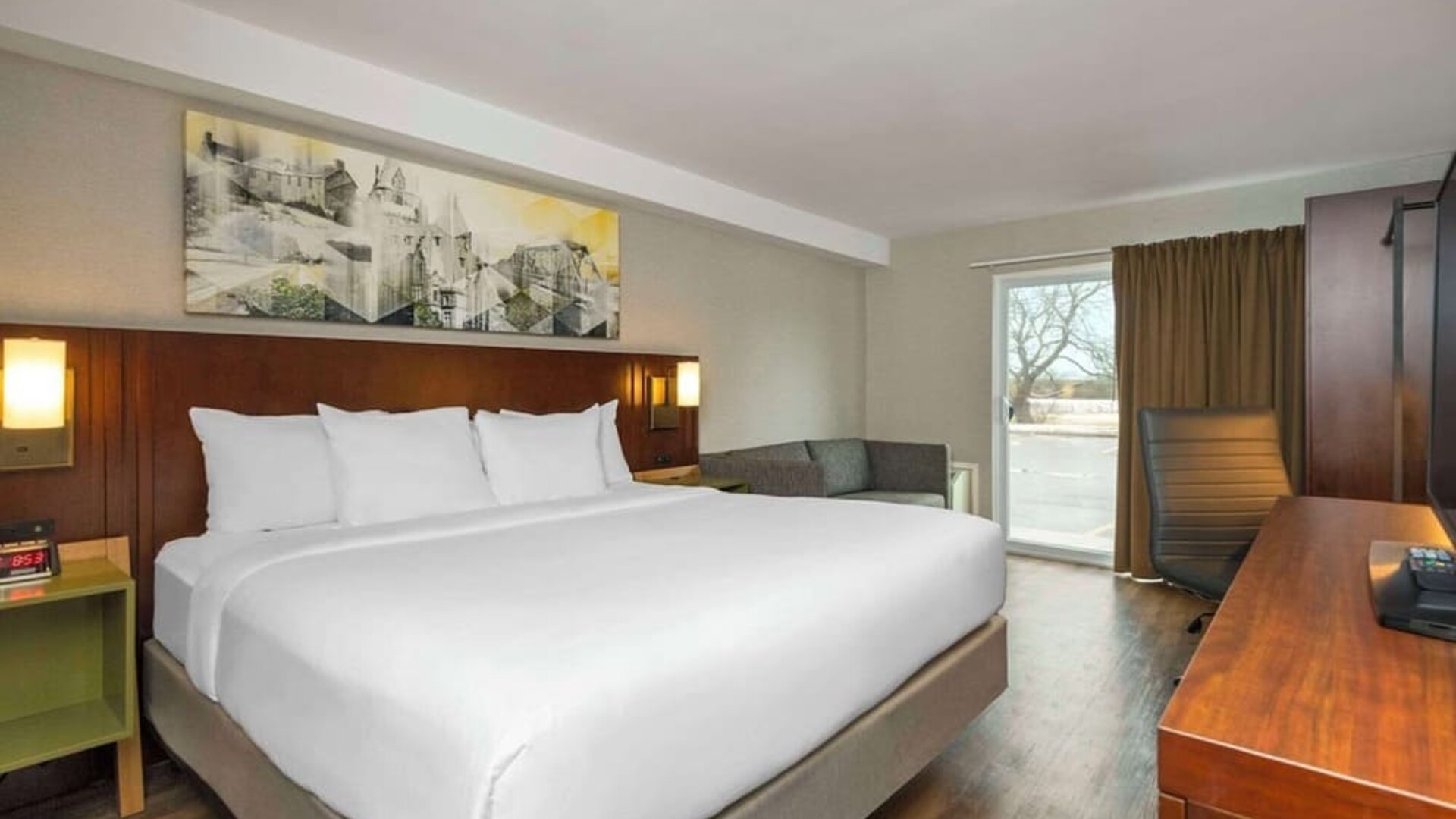 King guest room with a sofa, work desk, and window seating area at Comfort Inn Brossard.
