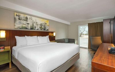 King guest room with a sofa, work desk, and window seating area at Comfort Inn Brossard.