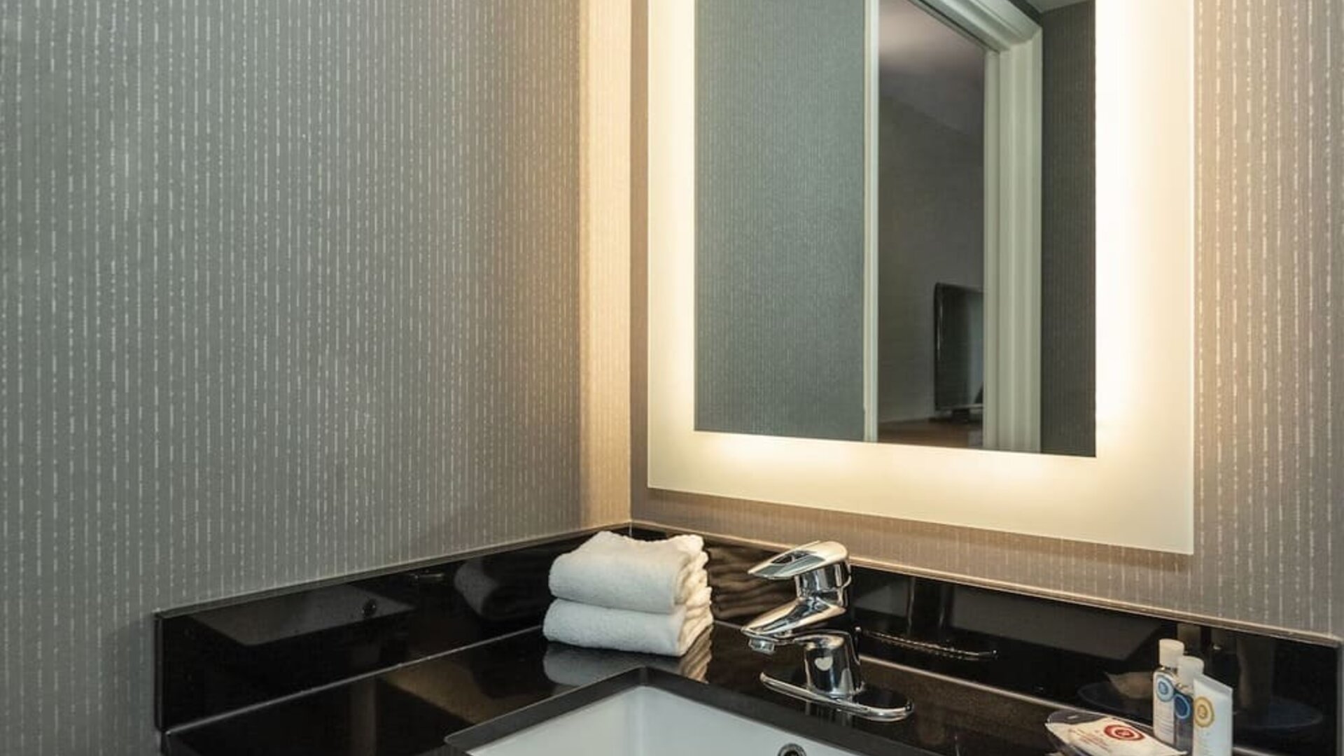 Guest bathroom vanity with an illuminated mirror at Comfort Inn Brossard.