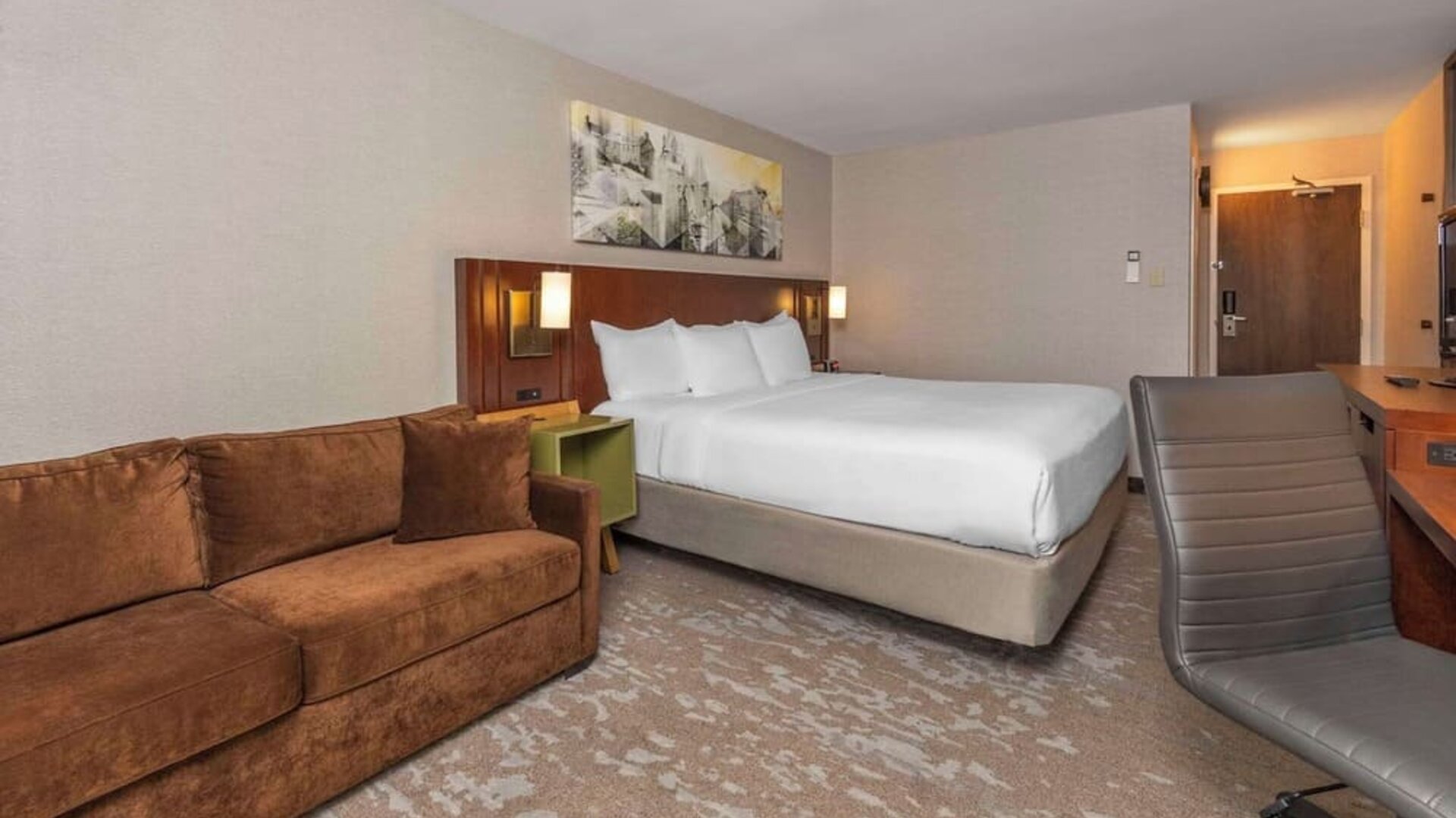 Spacious guest room with a king bed, sofa, and work desk at Comfort Inn Brossard.