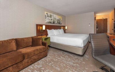 Spacious guest room with a king bed, sofa, and work desk at Comfort Inn Brossard.