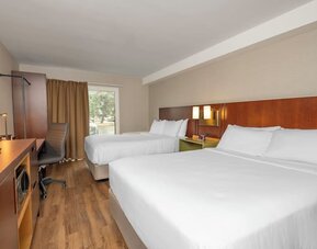 Guest room with two queen beds, TV, and work desk at Comfort Inn Brossard.