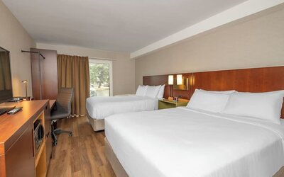 Guest room with two queen beds, TV, and work desk at Comfort Inn Brossard.