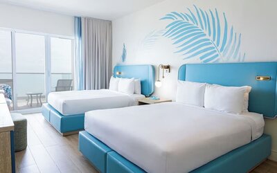 Guest room with two queen beds and a private balcony at Sherry Frontenac Oceanfront Hotel.