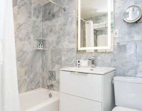 Guest bathroom with a bathtub and marble-style tile walls at Sherry Frontenac Oceanfront Hotel.