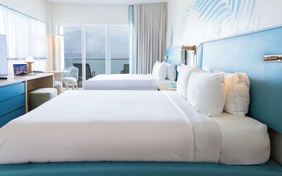 Oceanfront guest room with two queen beds and balcony access at Sherry Frontenac Oceanfront Hotel.