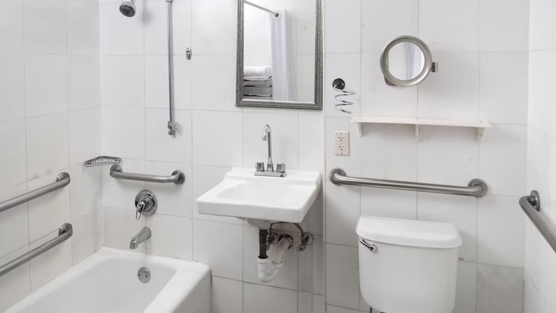 Accessible guest bathroom with grab bars and a bathtub at Sherry Frontenac Oceanfront Hotel.