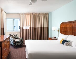 Guest room with a king bed and armchair at Sherry Frontenac Oceanfront Hotel.