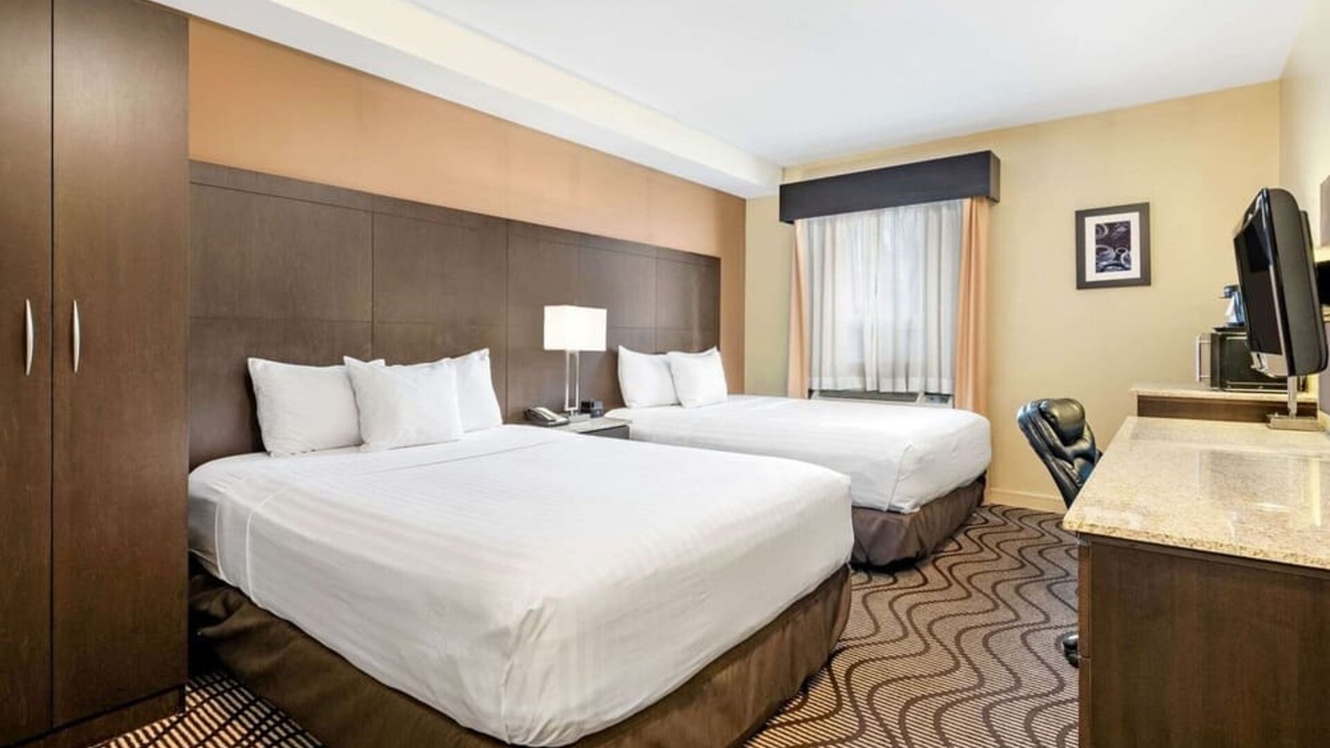 Guest room with two queen beds and bedside table at La Quinta Inn & Suites By Wyndham Oshawa.