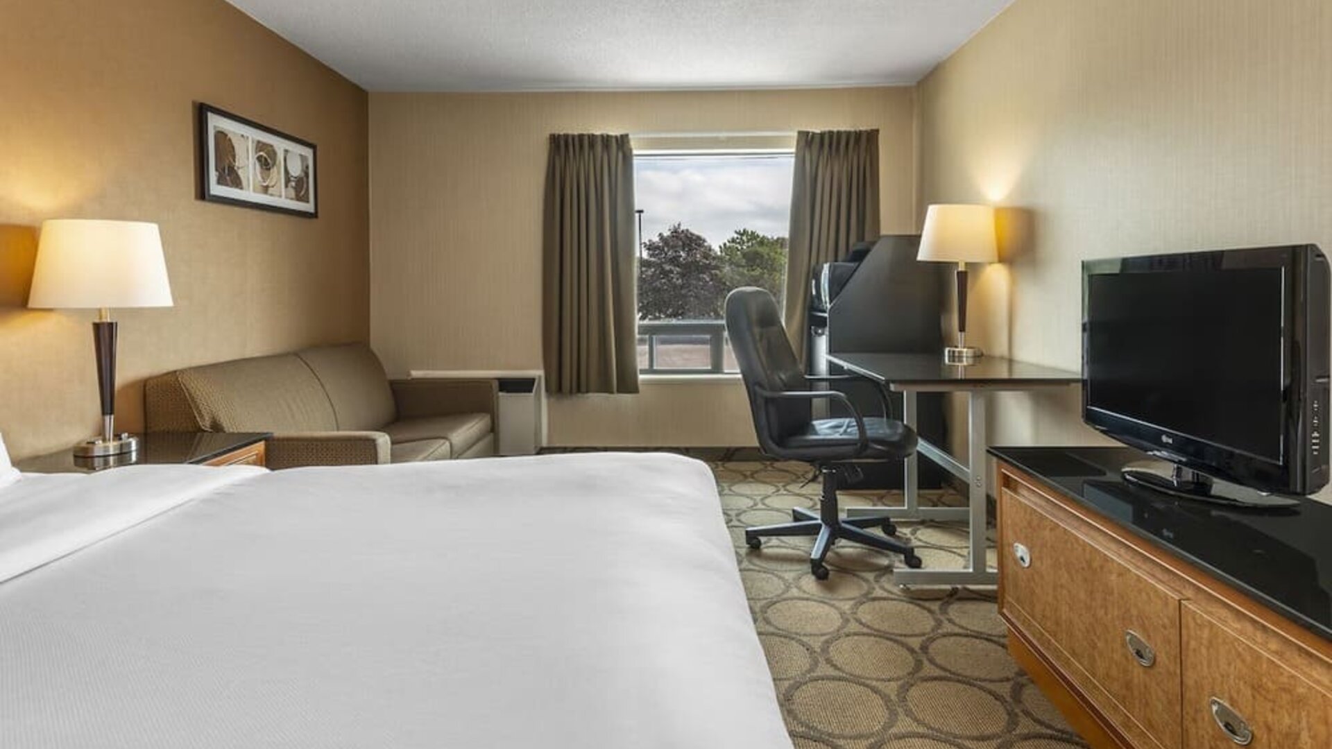 Guest room with a king bed, sofa, and work desk at Comfort Inn Prince Albert.