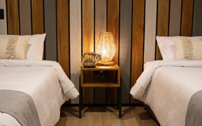 Guest room with two single beds, striped wood headboard and illuminated bedside table at Marbore Hotel & Spa.