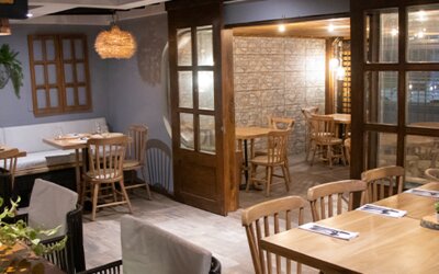 Warmly lit restaurant with wooden tables, enclosed dining spaces and decorative pendant lighting at Marbore Hotel & Spa.