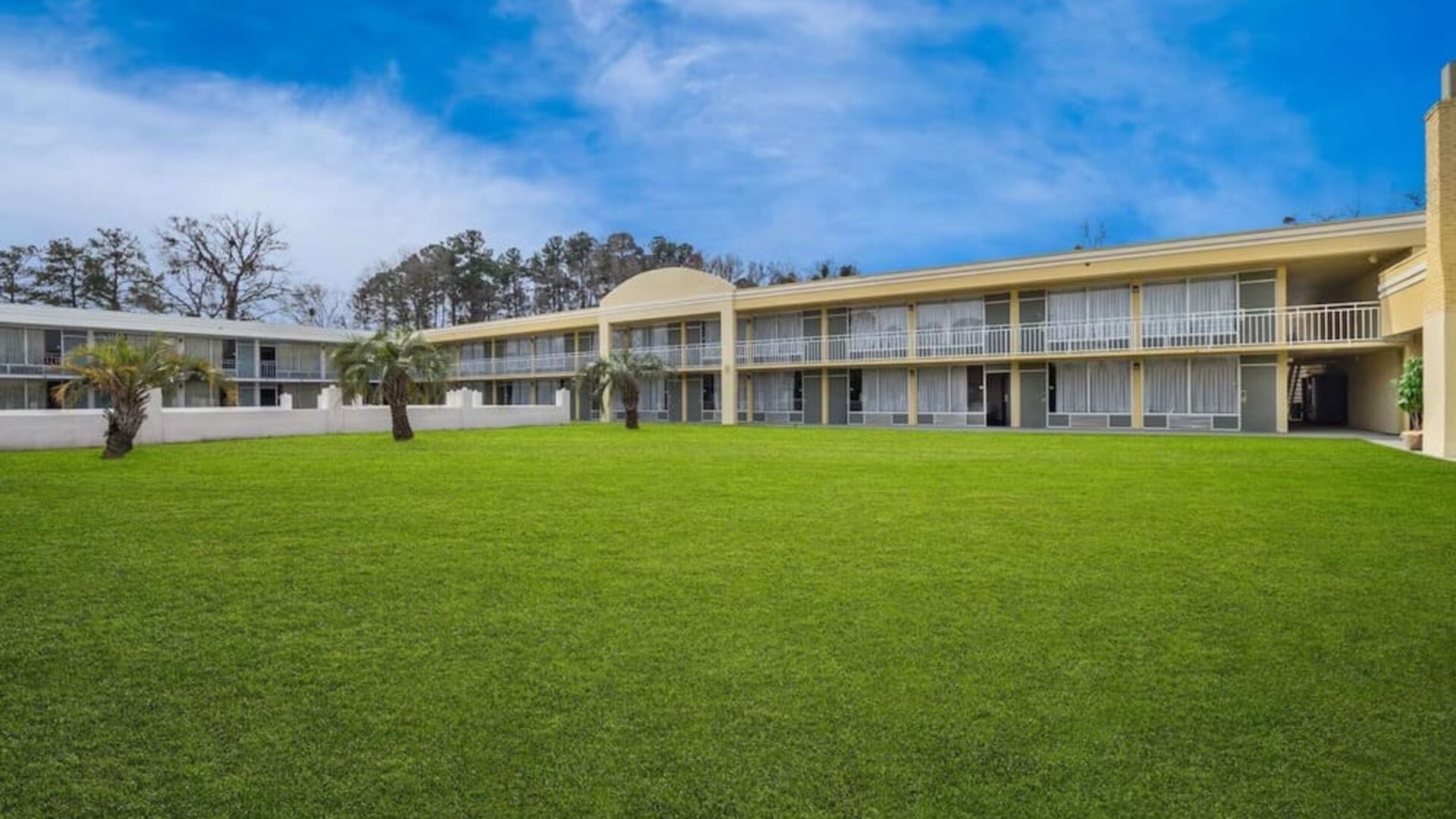 Two-story hotel exterior overlooking a large grassy courtyard with palm trees at Quality Inn Yemassee - Point South I-95.