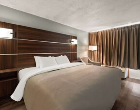 King guest room with dark wood headboard, bedside lighting and blackout curtains at Quality Inn Yemassee - Point South I-95.